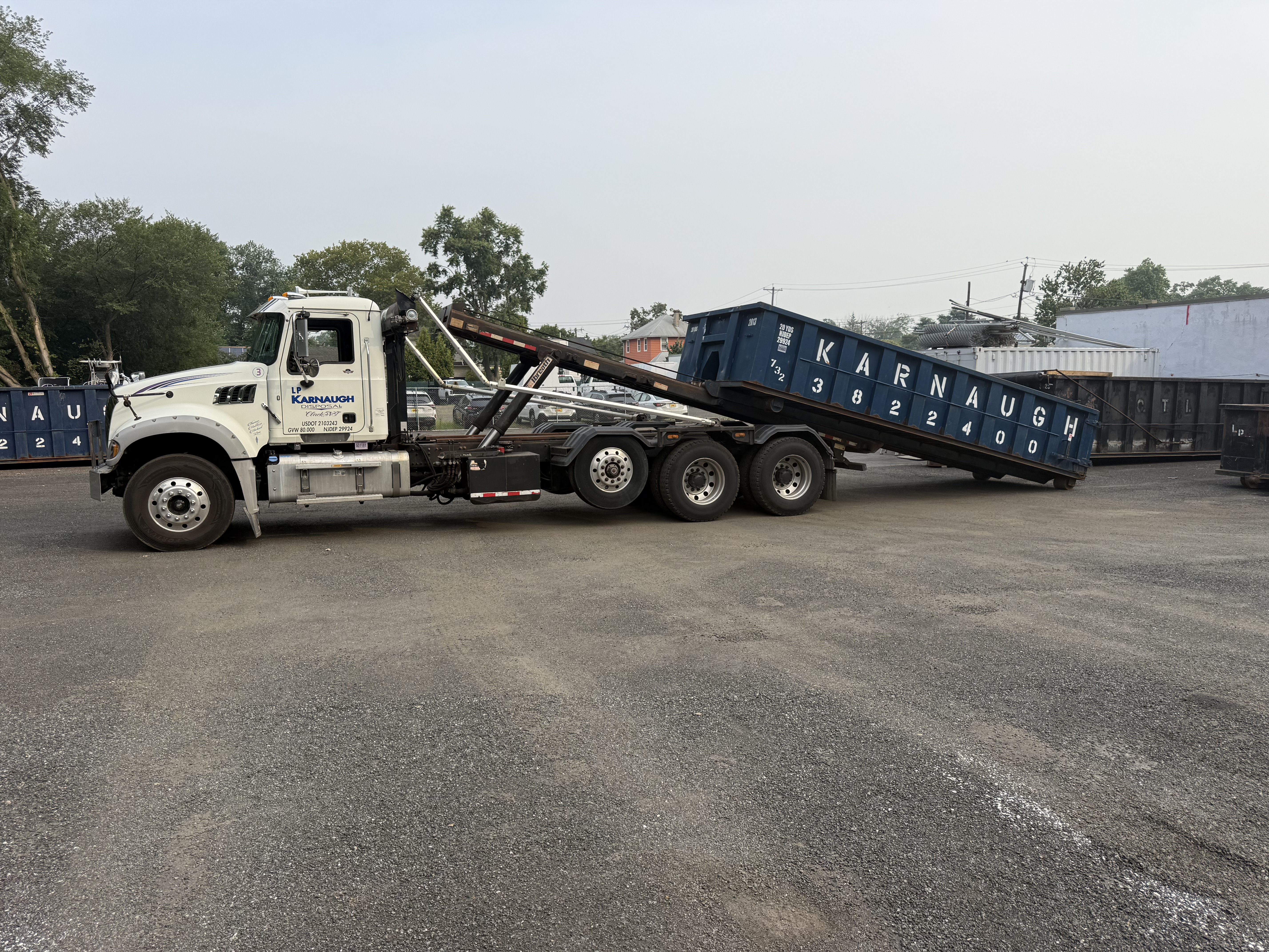 Dumpster being delivered halfway off truck - LP Karnaugh Disposal